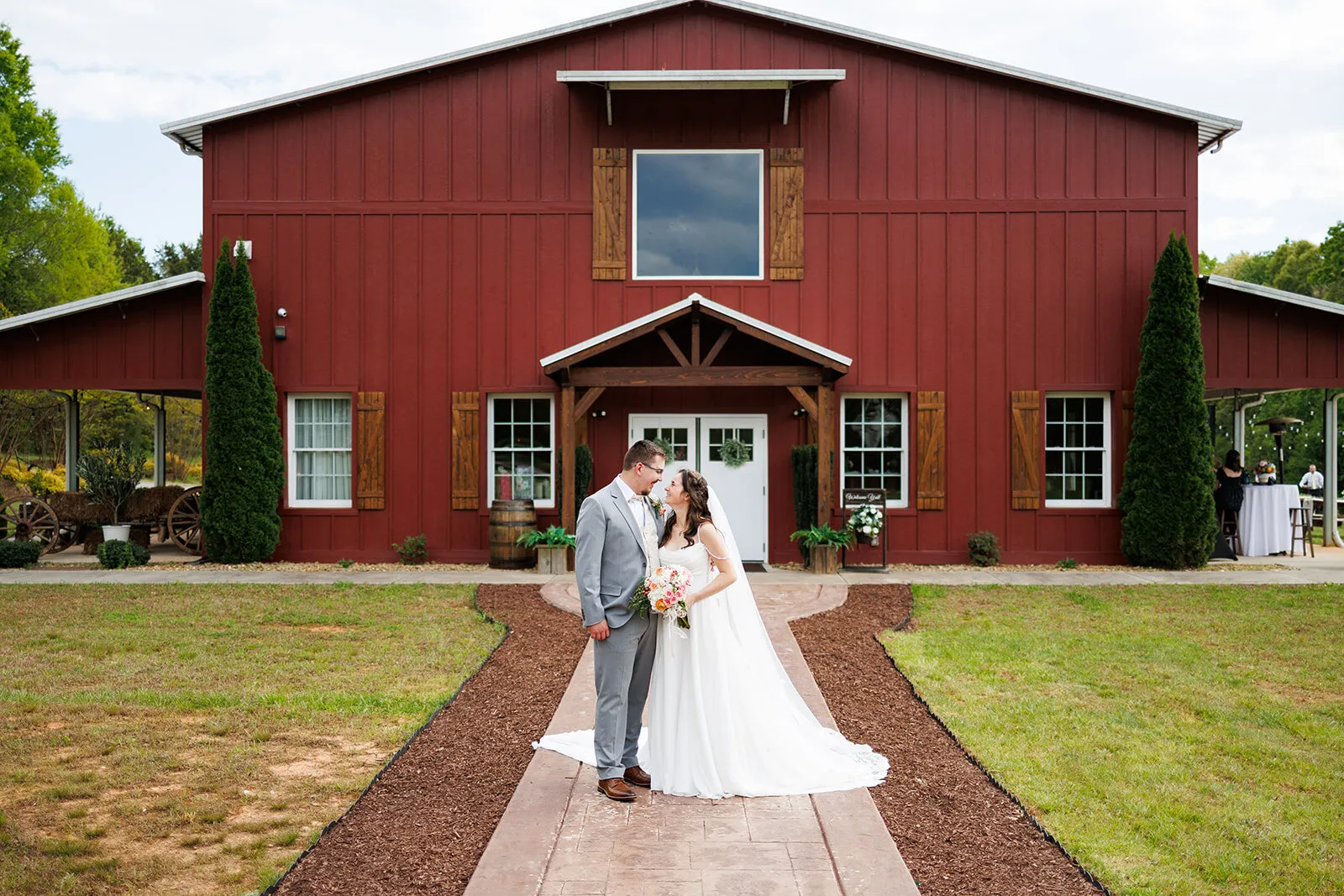 Couple walking toward the red barn ceremony at The Heritage Barn wedding venue, Conover NC