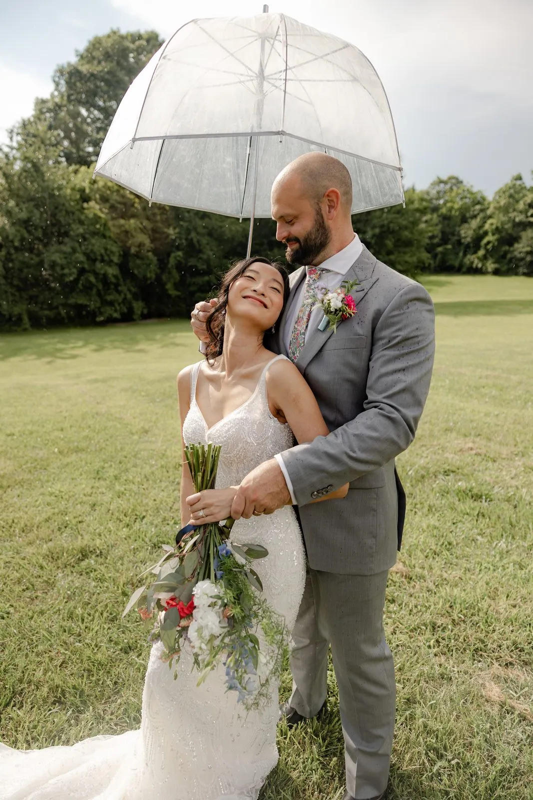 Bride and groom under a clear umbrella at The Heritage Barn