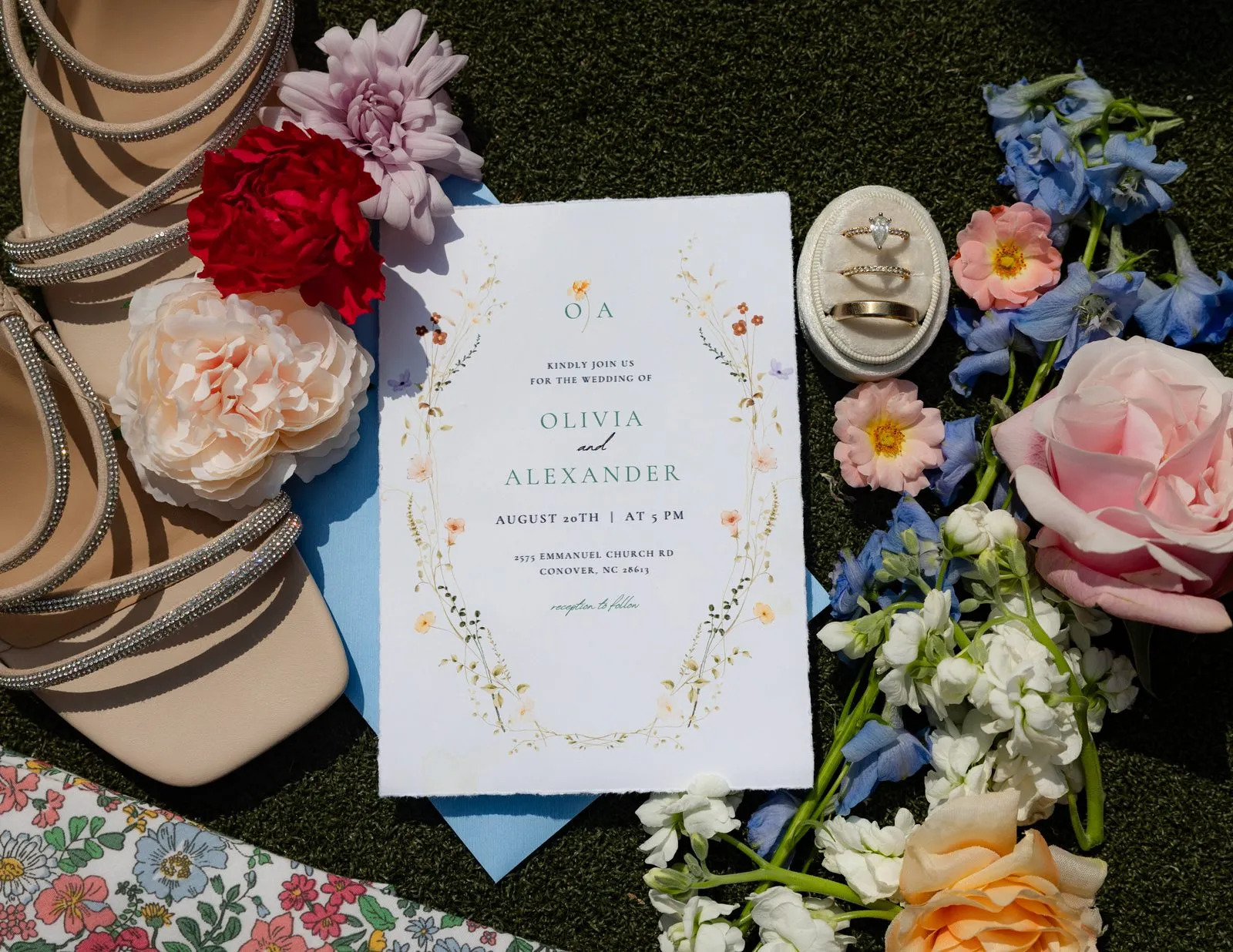 Colorful wedding invitation suite flat lay styled with florals and rings at The Heritage Barn