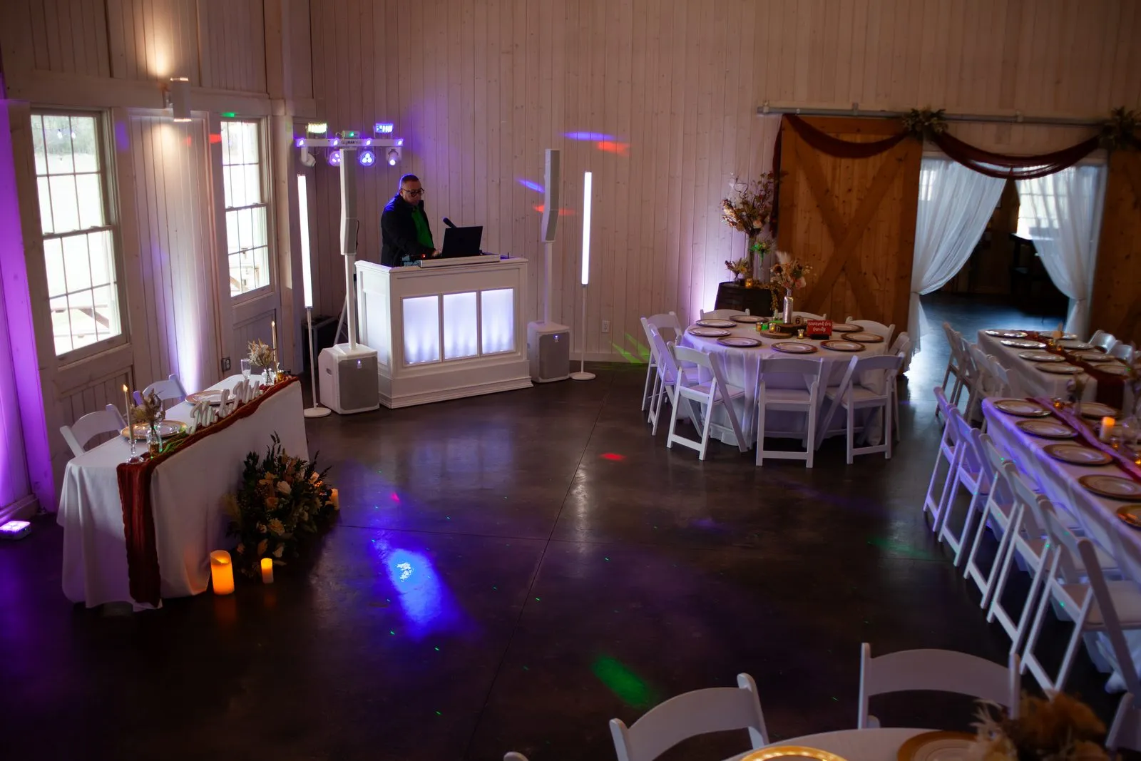 Barn reception and dance floor glowing with colored uplighting at The Heritage Barn