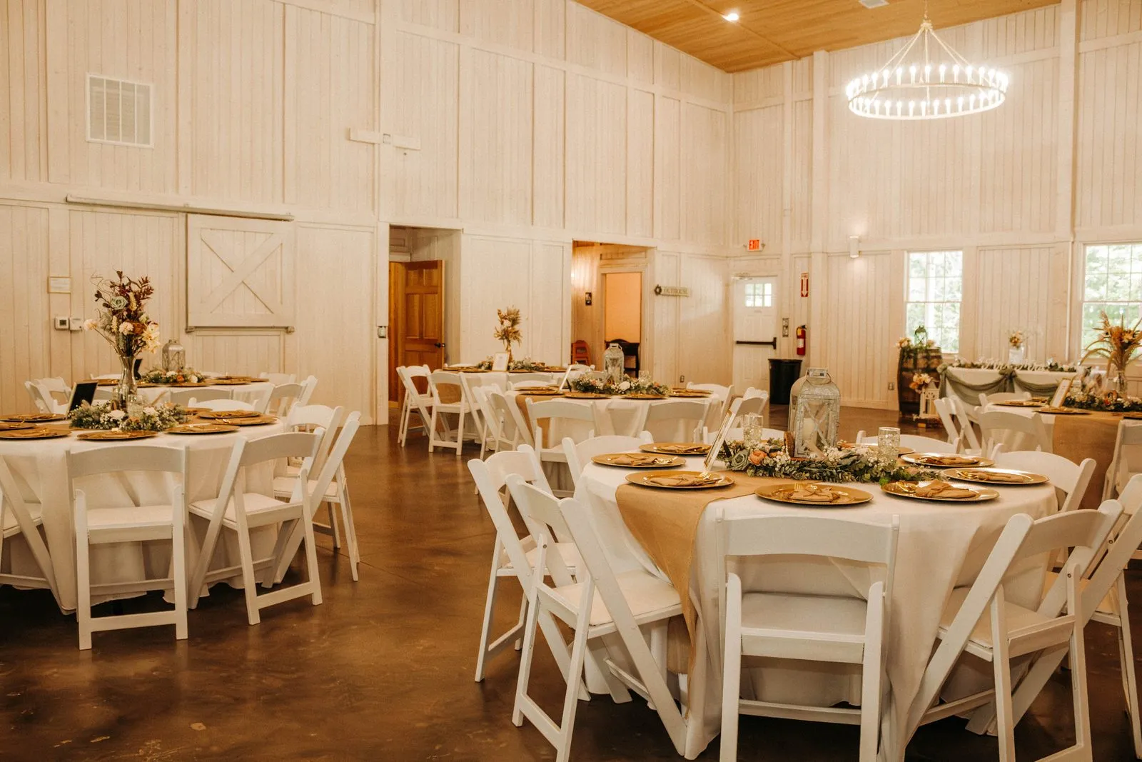 Round reception tables set inside the bright, climate-controlled barn at The Heritage Barn